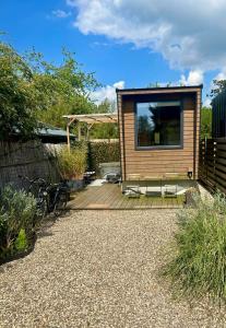 a tiny house with a large window on a wooden deck at Tiny house with garden and jacuzzi near Amsterdam in Vijfhuizen