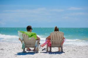 a man and woman sitting in chairs on the beach at Living the Dream in Siesta Key