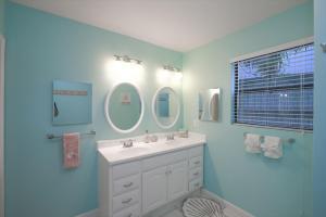 a bathroom with a white sink and two mirrors at Living the Dream in Siesta Key