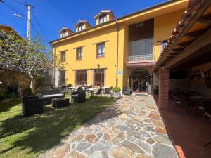 un edificio amarillo con un patio con sillas y mesas en Hotel Gavitu en Celorio