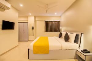 a bedroom with a large bed with a yellow blanket at Housemate Hotel in Pune