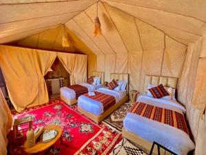 a group of four beds in a tent at Sahara Luxury Camp & Camel Trek in Merzouga