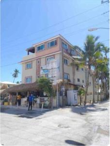un grande edificio con palme di fronte di Hostal Las Rosas de Punta Cana a Punta Cana