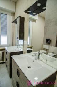 La salle de bains est pourvue de 2 lavabos et d'un grand miroir. dans l'établissement Residenza Gramsci 13, à Parme