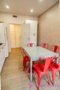 - une table blanche et des chaises rouges dans la chambre dans l'établissement Residenza Gramsci 13, à Parme