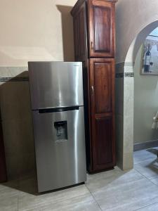 a stainless steel refrigerator next to a wooden cabinet at White House by White River in Ocho Rios