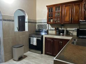a kitchen with wooden cabinets and a black stove at White House by White River in Ocho Rios