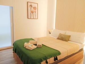 een kleine slaapkamer met een bed met een groene deken bij Annamaria B&B Alicante Centro in Alicante