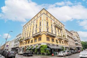 Un edificio amarillo en una calle de la ciudad con coches aparcados. en Nice apartment in Milan Porta Venezia Duomo, en Milán