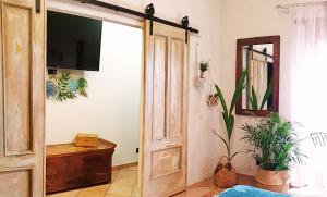 Habitación con puerta abierta, TV y plantas. en Mialma Rome Holiday Home Casa lontano da casa, en Ciampino