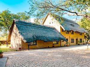 a large yellow building with a thatched roof at Mopani Lodge Victoria Falls in Victoria Falls