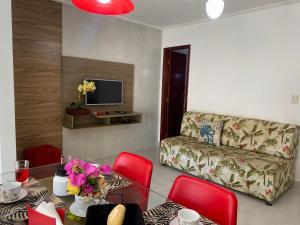 a living room with a couch and a table with red chairs at Mar Y Suites in Cabo Frio