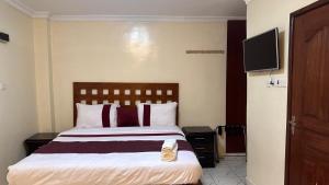 um quarto de hotel com uma cama e uma televisão de ecrã plano em White Star Hotel em Nairobi