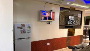 TV colgada en una pared con nevera en White Star Hotel, en Nairobi