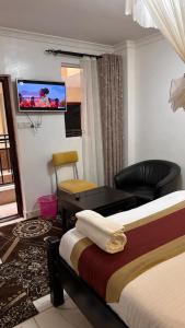 Habitación de hotel con cama y TV en la pared en White Star Hotel, en Nairobi