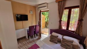 a bedroom with a bed and chairs and a television at Pansion Oscar Summer Garden in Mostar