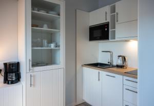 a kitchen with white cabinets and a counter top at Appartementhaus Westerloog 20 in Spiekeroog