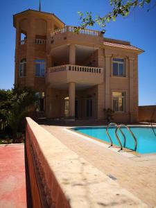 a building with a swimming pool in front of a house at ساحل الشمالي قريه امون in Qaryat Shurūq