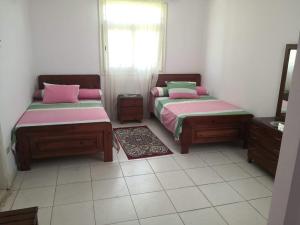 a room with two beds with pink and green sheets at ساحل الشمالي قريه امون in Qaryat Shurūq
