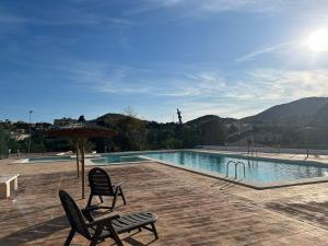 a swimming pool with two chairs and an umbrella at la casa de Adela - Cala lanuza in El Campello