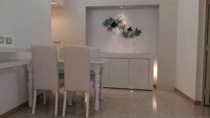a dining room with a table and white chairs at Casa Per 2 in Porto Santo Stefano +4 photos