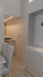 a white kitchen with white chairs and a counter at Casa Per 2 in Porto Santo Stefano