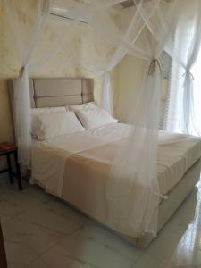 a bedroom with a white bed with curtains and a window at La Casa in Villaggio Tedeschi