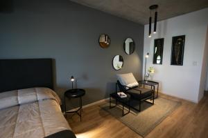 um quarto com uma cama, uma cadeira e espelhos em UNDICI By OWN Republica de la Boca em Buenos Aires