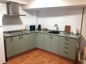 uma cozinha com armários brancos, um lavatório e um micro-ondas em Casa Puri em Jérica