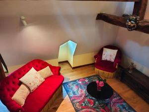 a living room with a red couch and two chairs at Le logis Bodard Appartement centre ville dans un hôtel particulier XIVeme avec parking et locale vélo in Chinon
