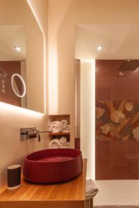 La salle de bains est pourvue d'un lavabo rouge et d'une douche. dans l'établissement BeBari Apartments, à Bari