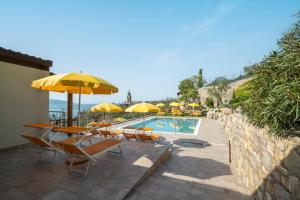 una piscina con mesas, sillas y sombrillas en Residence Dany appartamenti con cucina vista lago piscina e parcheggio, en Gargnano