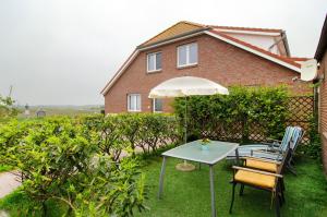 a table and chairs with an umbrella in front of a house at Opashus in Borkum