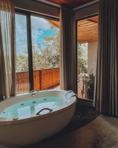 een badkuip in een kamer met een groot raam bij Vila Baru in Alto Paraíso de Goiás