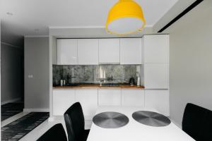 a kitchen with white cabinets and a table and chairs at Noclegi Staś Krasnobród in Krasnobród