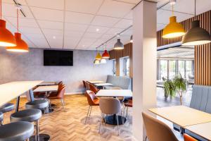 un restaurant avec des tables et des chaises et une télévision à écran plat dans l'établissement ibis budget Derby, à Derby
