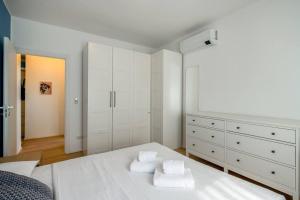 ein Schlafzimmer mit einem weißen Bett und weißen Schränken in der Unterkunft Ospedale Niguarda - Moderno Appartamento a Milano by Hôtea in Mailand + 25 Fotos