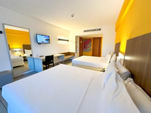 a hotel room with two beds and a television at Enotel Porto de Galinhas All Inclusive in Porto De Galinhas