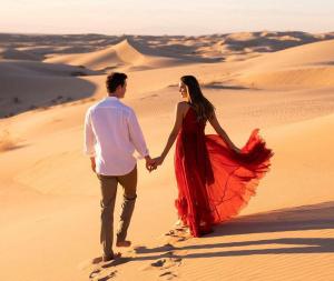 un hombre y una mujer caminando por el desierto en Merzouga luxury magic nights, en Merzouga