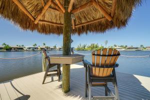two chairs and a table on a deck with the water at Cape Coral Home on Lake with Heated Pool and Hot Tub! in Matlacha