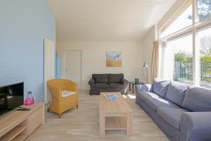 ein Wohnzimmer mit einem Sofa und einem Tisch in der Unterkunft Vakantiehuis Duynloper - Julianadorp aan Zee in Julianadorp