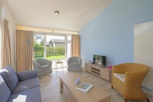 ein Wohnzimmer mit einem Sofa und einem TV in der Unterkunft Vakantiehuis Duynloper - Julianadorp aan Zee in Julianadorp