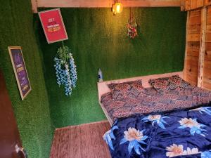 a bedroom with a bed and a green wall at Shanti People Huts & Camp in Kasol