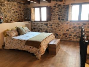 1 dormitorio con cama y pared de piedra en Casa Puri en Jérica