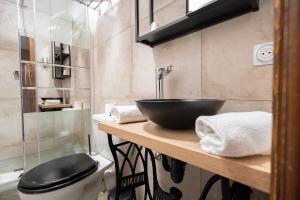 a bathroom with a black bowl sink and a toilet at Hôtel Berceau Du Vigneron in Turckheim
