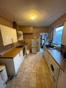 cocina con armarios blancos y lavadora en Luton Airport - Affordable Home, en Luton