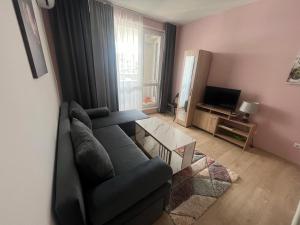 uma sala de estar com um sofá e uma televisão em Апартамент за гости Incanto del mare em Sarafovo