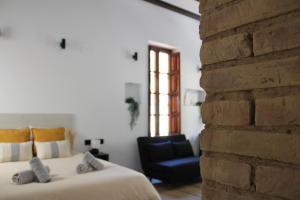 ein Schlafzimmer mit einem Bett und einem Stuhl neben einer Ziegelwand in der Unterkunft Las Arenas Suites 1 PLAYA in Valencia