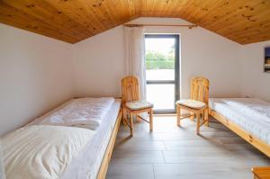 deux lits dans une chambre avec deux chaises et une fenêtre dans l'établissement FeWo Breuker, à Kellenhusen