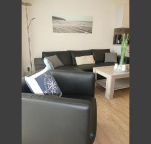 a living room with a black couch and a table at Quartier Hohe Geest 17 - Nord Seestern - a69854 in Cuxhaven